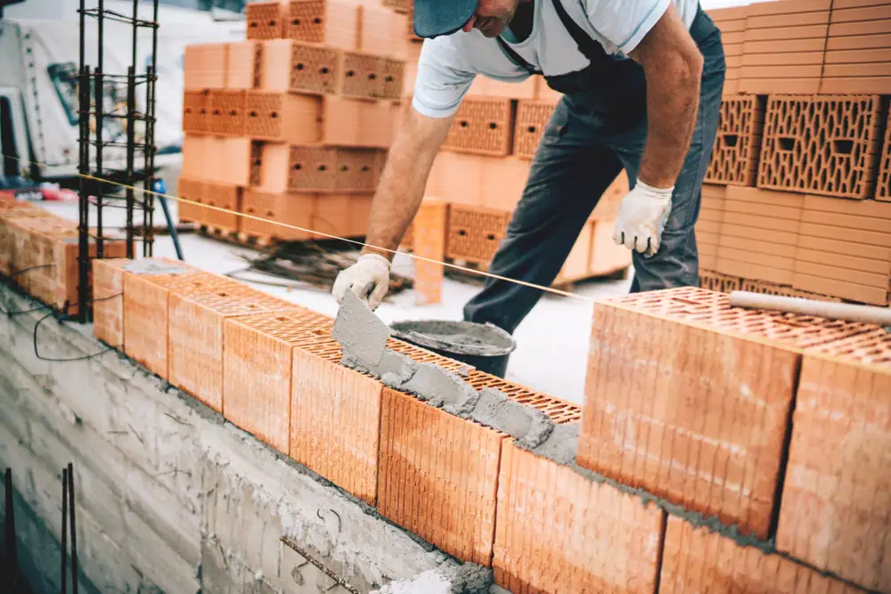 Skilled bricklayer constructing a sturdy brick wall in Suffolk County, New York, showcasing precision and craftsmanship for Power House Mason Supply