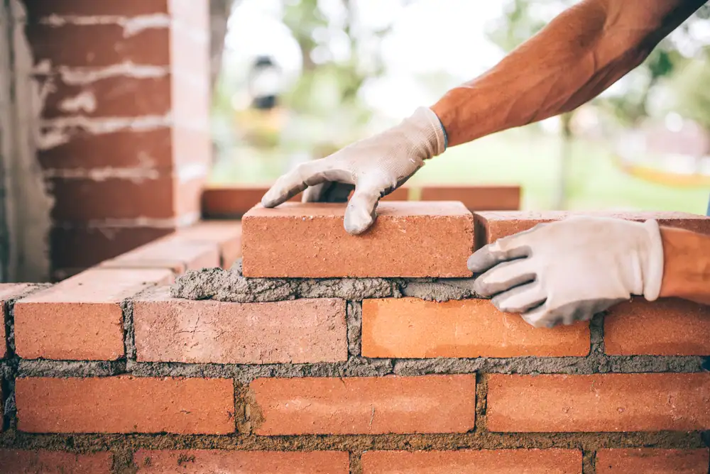 Skilled bricklaying construction worker in Suffolk County, New York, expertly laying bricks for a masonry project, with Power House Mason Supply materials in use